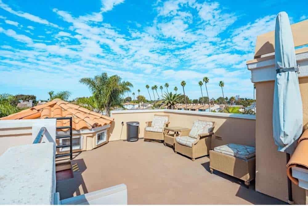 Outdoor rooftop lounge area with cozy seating and palm tree views at a Huntington Beach alcohol rehab, offering a serene environment for recovery.